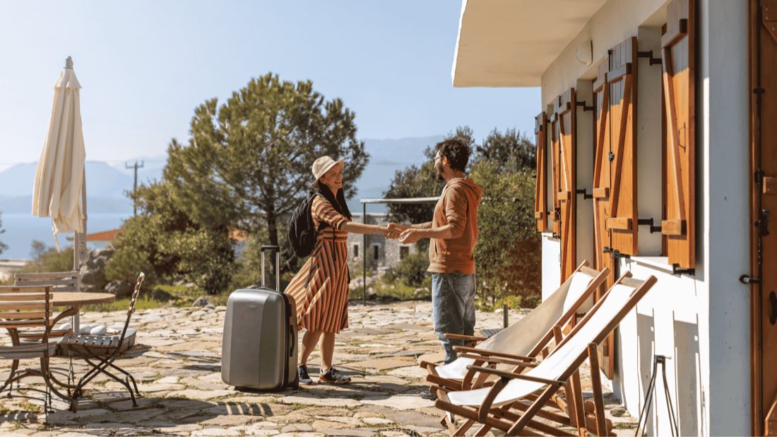 Pareja de huéspedes con maleta llegando a un apartamento turístico