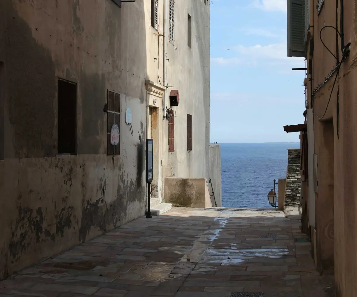 Callejón encalado de un pueblo costero con el mar al fondo